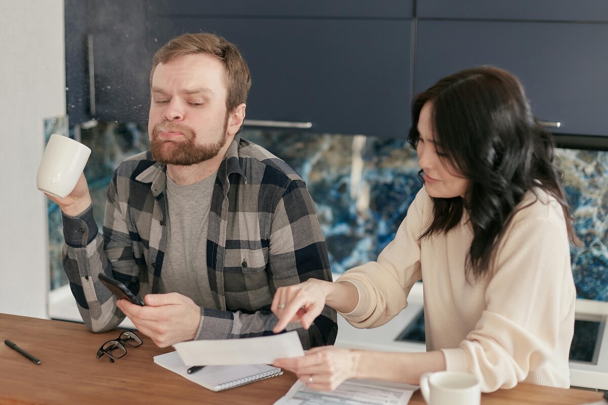 Pariskunta istuu pöydän ääressä ja keskustelee talousasioista